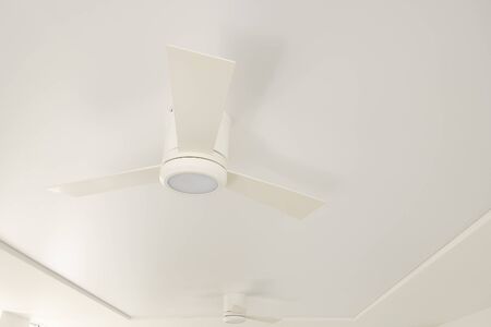 An overhead LED luminaire combined with a white ceiling fan on a white ceiling