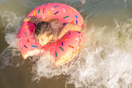 5 year old boy bathes in the sea in a life ring on a sunny day