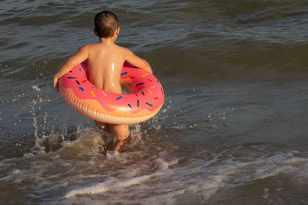A 5-year-old boy bathes in a donut-shaped life ring on a sunny day