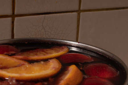Red wine mulled wine with apples and oranges in the process of making at home in a stainless steel saucepanの写真素材