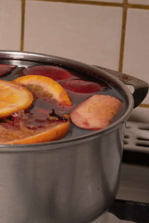 Red wine mulled wine with apples and oranges in the process of making at home in a stainless steel saucepanの写真素材
