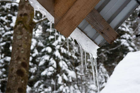 Wooden structure in the winter forest. Icicles on the roof. They ate in the snow