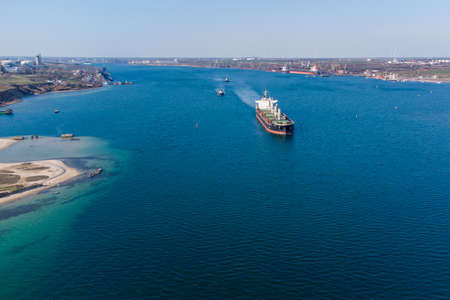 The dry cargo vessel enters the port with the help of tugs. Photo from a helicopter. Bird's-eye view