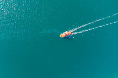 The pilot boat orange goes to meet the vessel on the outer roads. Helicopter view. Top view of the seaの写真素材