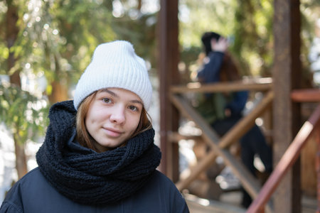 Two girls in winter on the terrace of a wooden house in a folk style. Selective focusの写真素材