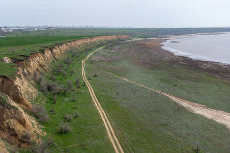The coast of the Kuyalnitsky estuary in the spring. Sandy cliff, beach and pond. Aerial viewの写真素材