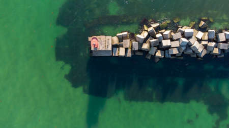 A breakwater made of white concrete cubes and a leading sign at the entrance to the port of Yuzhny....