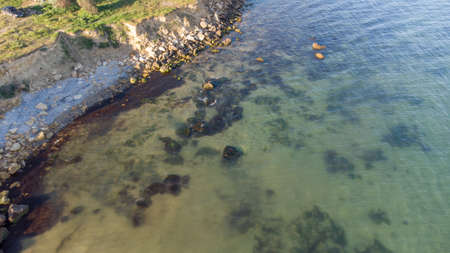 Aerial view of the stony seashore. Transparent water and stones in the waterの写真素材