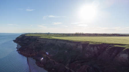 Steep sandy cliff on the seashore at sunriseの写真素材
