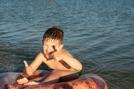 A boy of 6 years old swims on an inflatable ring in the sea near the shoreの写真素材