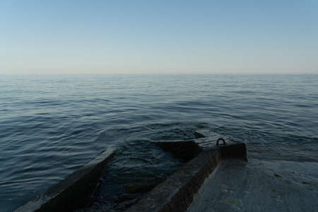 Sea waves run into a concrete pier. Night sea