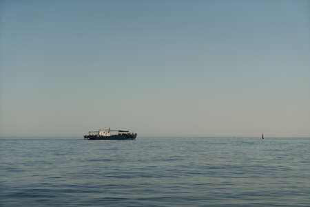 Small marine boat in the sea on the horizon at sunriseの写真素材