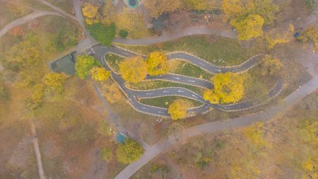 Bicycle path imitating a mountain serpentine track in the city park in autumn. Leaf fall in the park. Aerial viewの写真素材