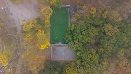 Football field with green grass and basketball court in city park in autumn. Leaf fall in the park. Aerial viewの写真素材