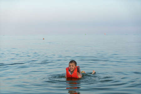 A 5 year old boy is kept on the water in the sea with the help of a life jacketの写真素材