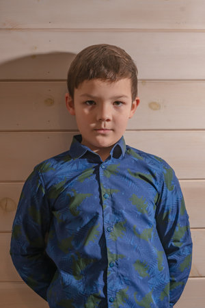 Portrait of a boy 8 years old brunette in a blue shirt. A very serious lookの写真素材