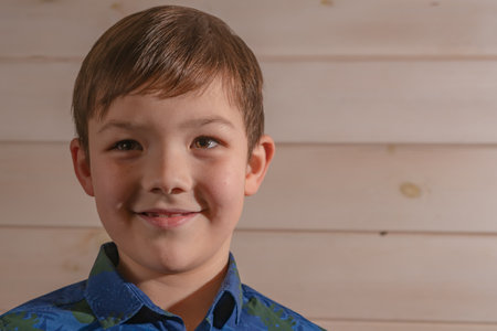 Portrait of a boy 8 years old brunette in a blue shirt. Smiling with closed lipsの写真素材