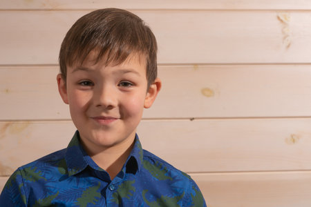 Portrait of a boy 8 years old brunette in a blue shirt. Smiling with closed lipsの写真素材