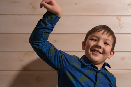 Portrait of a boy 8 years old brunette in a blue shirt. Shows two fingersの写真素材