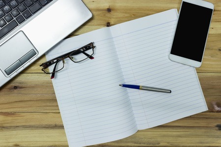 Top view of a wooden desk with office supplies placed.の写真素材