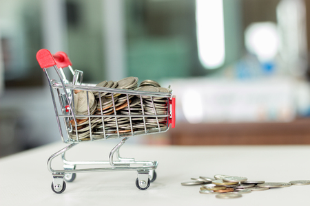 Shopping Cart has coins in the shopping cart on the table.の写真素材