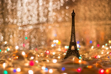 The Eiffel model is placed on a wooden table surrounded by light. Blurry background.の写真素材