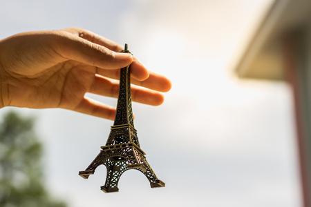 Hands catching Eiffel model held up in the sky.の写真素材