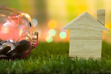 Saving money for the future for housing has piggy bank and house models placed on artificial grass.の写真素材