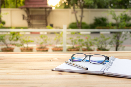 A desk with pen book and eyeglasses is placed for notes.の写真素材