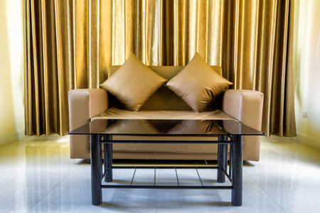 The sofa in the room has a golden curtain as the background.の写真素材