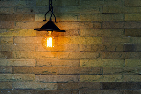 The metal lamps are hanging the interior decoration is illuminated by electric light bulb of background are brick-style loft retro vintage walls in room and the space is filled with text.の写真素材