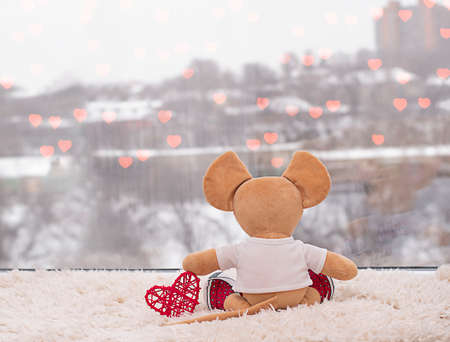 plush toy mouse with a red heart looks out the window. Valentines day conceptの写真素材