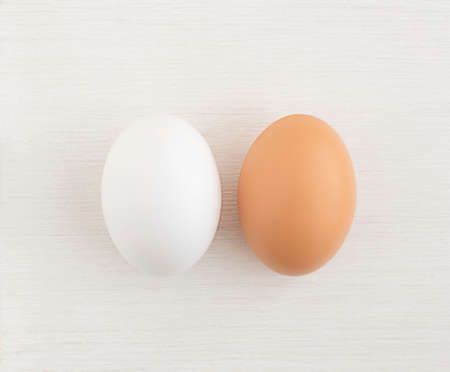 two Easter eggs white and brown on a white wooden background, close up. copy space.