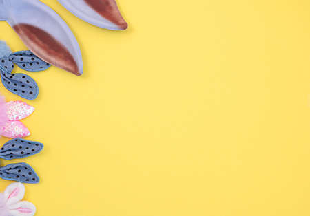 pink and blue fabric bunny ears on a yellow background. Easter concept.