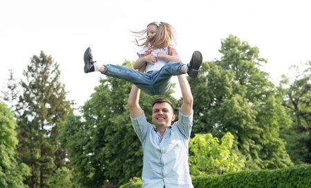 people. family concept. A happy and cheerful Caucasian man holds his little daughter high above his...