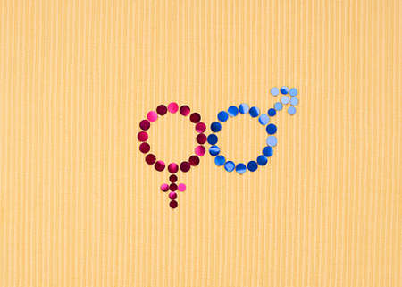 The concept of gender equality. Icon, logo made of pink and blue round tinsel on a yellow background. close-up. Women's Equality Day. copyspace. Horizontal. minimalism.の写真素材