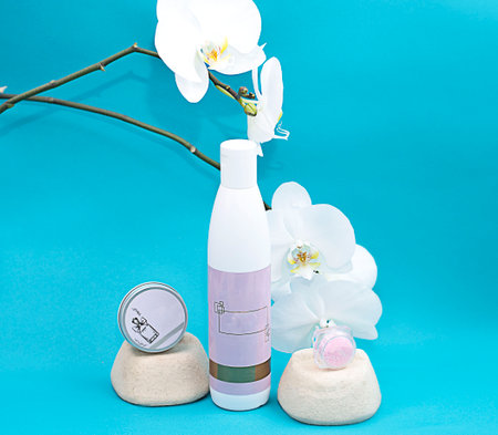 Layout. A set of cosmetic jars and bottles on a blue background next to a white orchid flower. Beauty concept.の写真素材