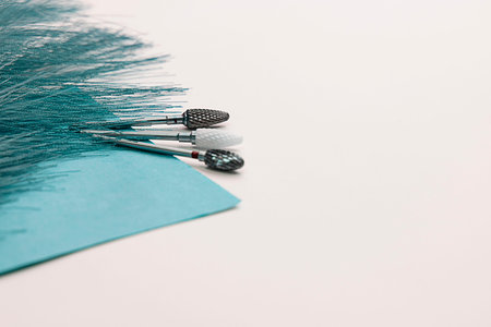 Three cutters for professional manicure lie on air sterilization paper next to a decorative feather on a white background.の写真素材