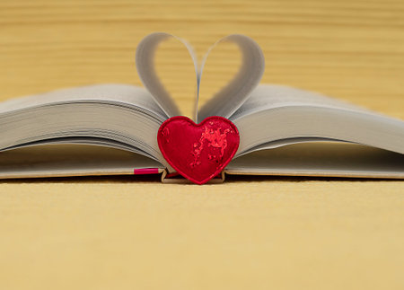 Valentine's day concept. red heart on the background of an open book. Heart from folded sheets. yellow background. heart symbol. close-up. soft focus.の写真素材