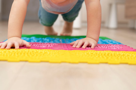 People. Health concept. A little boy stands in a plank on his hands on an orthopedic massage mat in a home interior.の写真素材