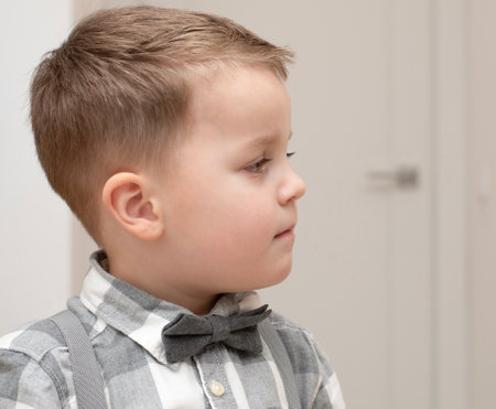 Emotions of calm, thoughtfulness on the child s face. A small handsome boy of 4 years old in a shirt with a bow tie shows a mime with a facial expression.の写真素材