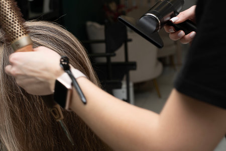 Beauty sphere. The master hairdresser does styling and combing the hair. Combs a clients long hair...