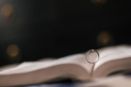 Wedding ring lies in the expanded Bible, a dark background, bokeh, macroの写真素材