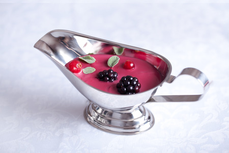 sauce with berries in a metal gravy boatの写真素材