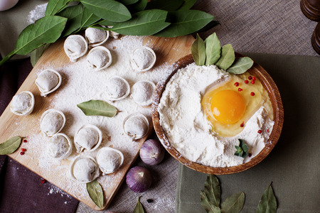 hand-made dumplings on the board with flour and ingredientsの写真素材