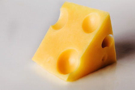 piece of cheese with holes on a white backgroundの写真素材