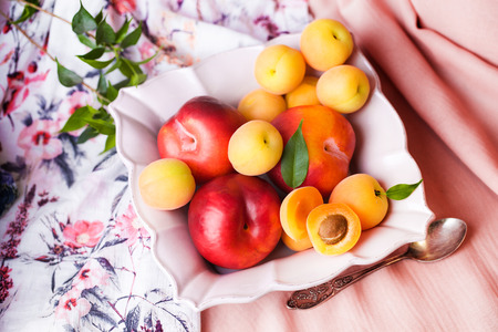 a plate of fresh peaches and apricots beautifulの写真素材