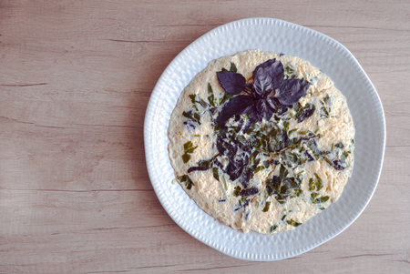 Tasty omelette from chicken eggs, milk and greens on a platter on a wooden table. View from above.の写真素材
