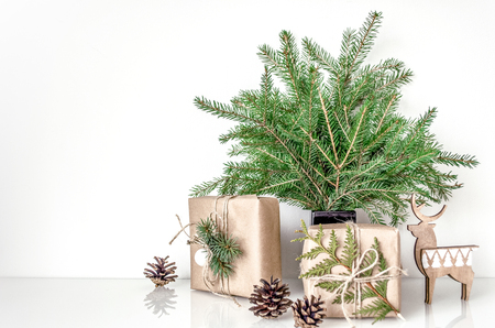 Christmas composition in Eco style. Spruce branches in the vase and gifts on the table in the interior. Template for displaying works. Copy space. Layout for displaying works.
の写真素材