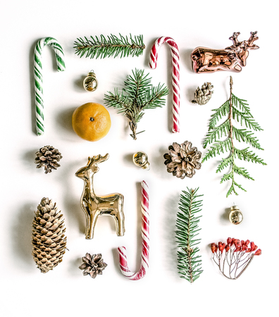 New Year's unusual composition with spruce branches, sweets, mandarin, cones and gold deer. View from above. Copy spaceの写真素材